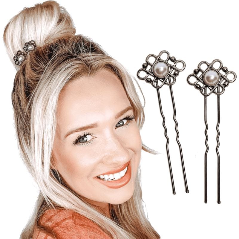 Two u-shaped hair pins with an antique pearl in the center, surrounded by a celtic-style design. 